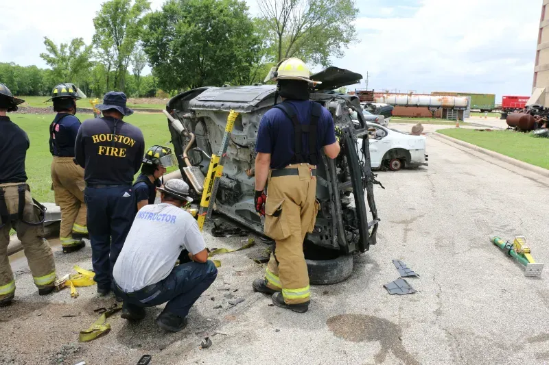 A group of firefighters are working on a staged wrecked car during an extrication exercise.