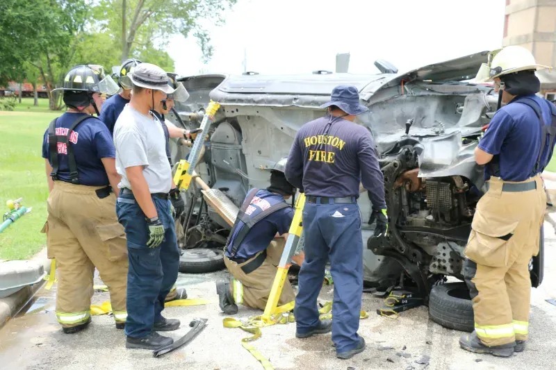 A group of firefighters are working on a staged wrecked car during an extrication exercise.