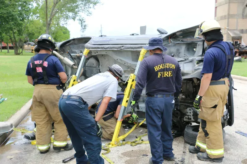 A group of firefighters are working on a staged wrecked car during an extrication exercise.