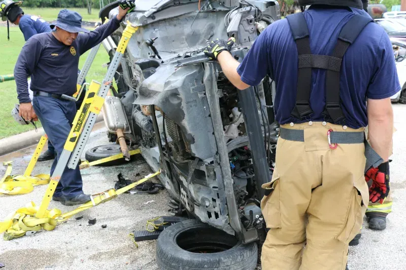 A group of firefighters are working on a staged wrecked car during an extrication exercise.