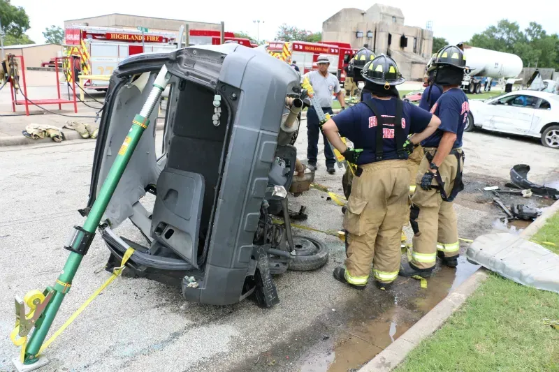 A group of firefighters are listening to an instructor during an extrication exercise.