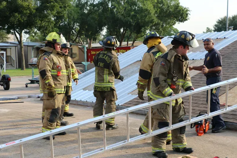 A group of firefighters are standing next to each other on a roof.