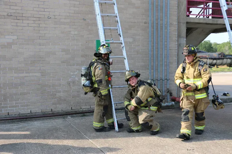 A group of firefighters are standing in front of a ladder.
