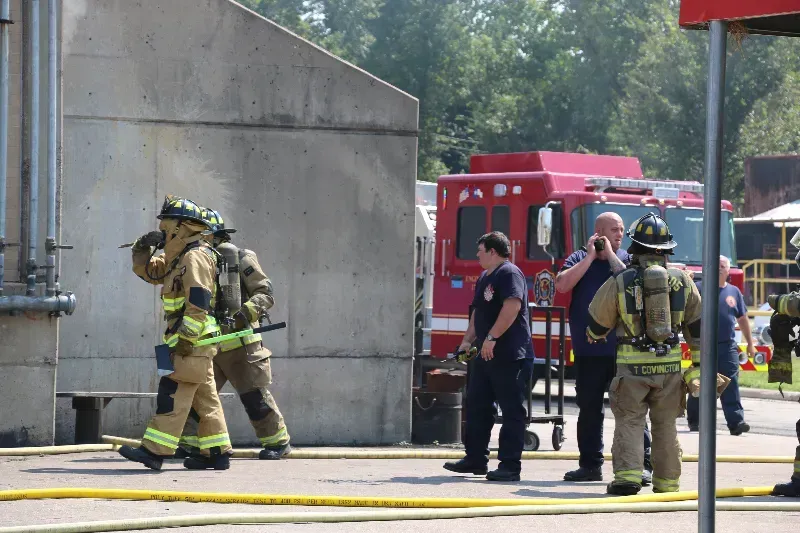 A group of firefighters are standing outside of a training building