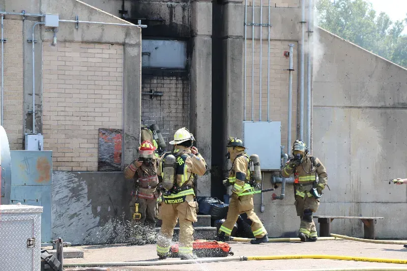 A group of firefighters are standing outside of a training building.