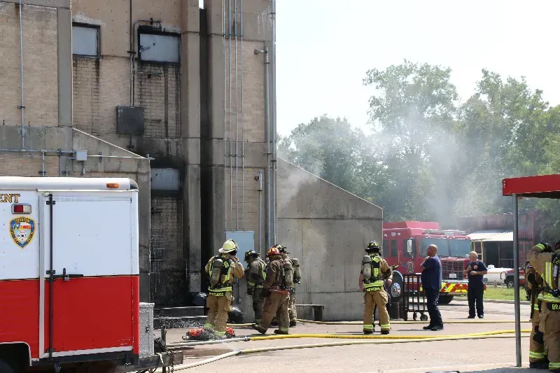 A group of firefighters are standing in front of a training building.