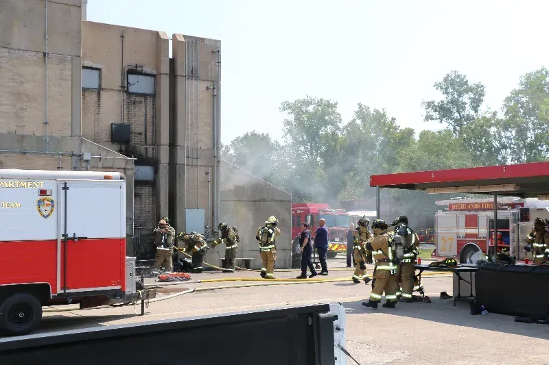 A group of firefighters are standing in front of a training building.