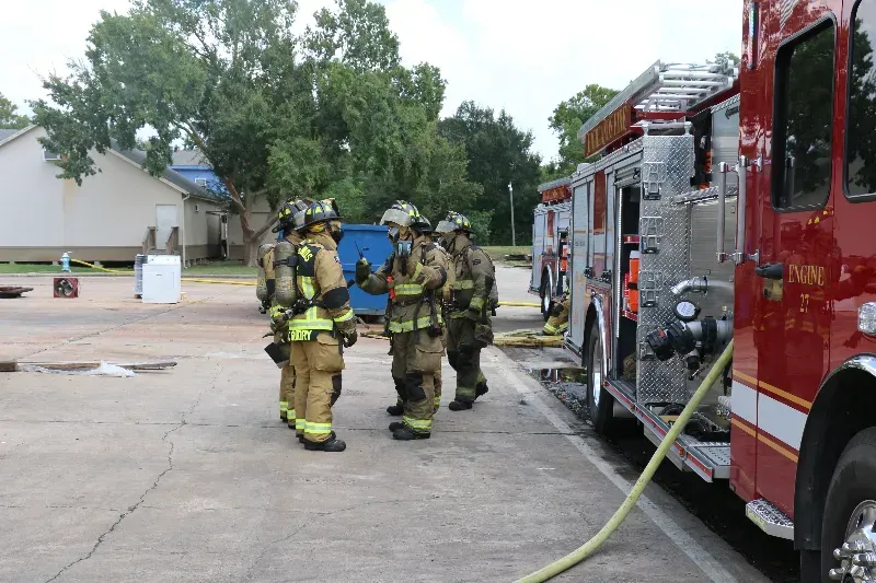 A group of firefighters are standing next to a fire truck.