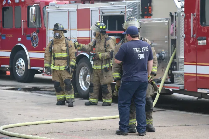 A group of firefighters are standing next to a fire truck.