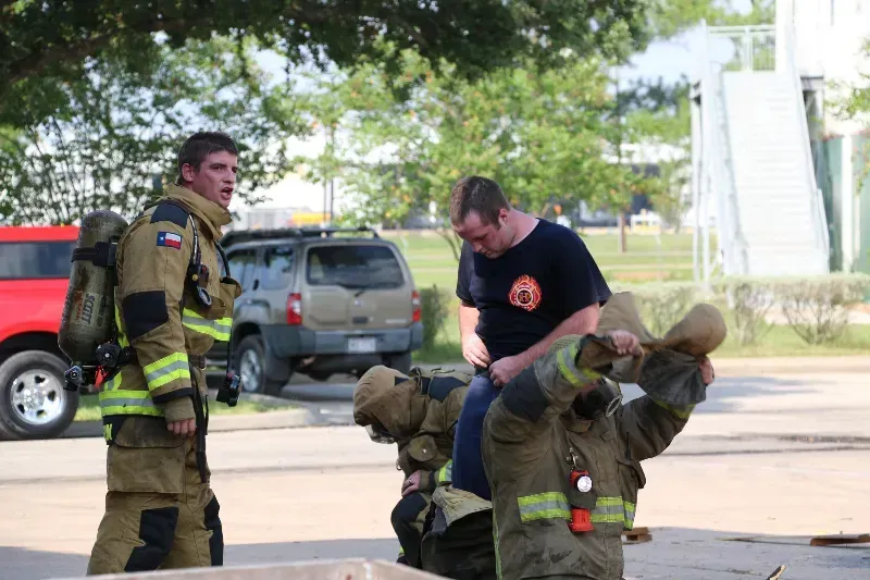 A group of firefighters are standing in a parking lot.