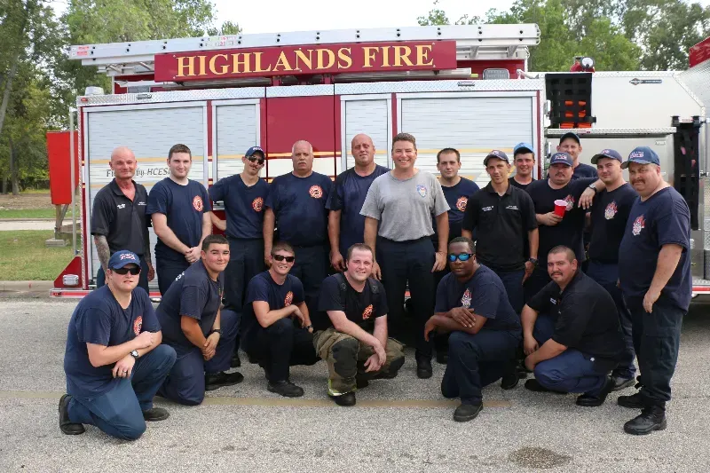 A group of firefighters posing in front of a Highlands fire truck