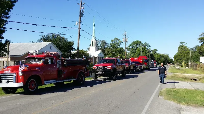 A row of fire trucks are lined up on the side of the road for a parade.