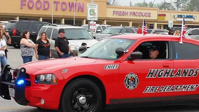 A red Highlands fire department car is driving in a parade line.