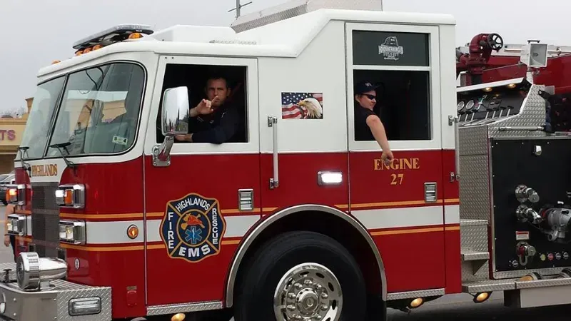 A red and white Highlands fire truck with the number 27 on it is driving in a parade.