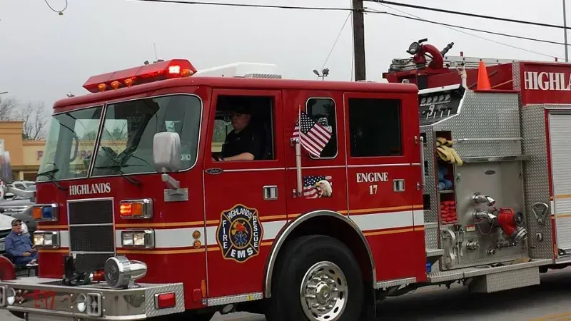 A red and white Highlands fire truck  is driving in a parade.