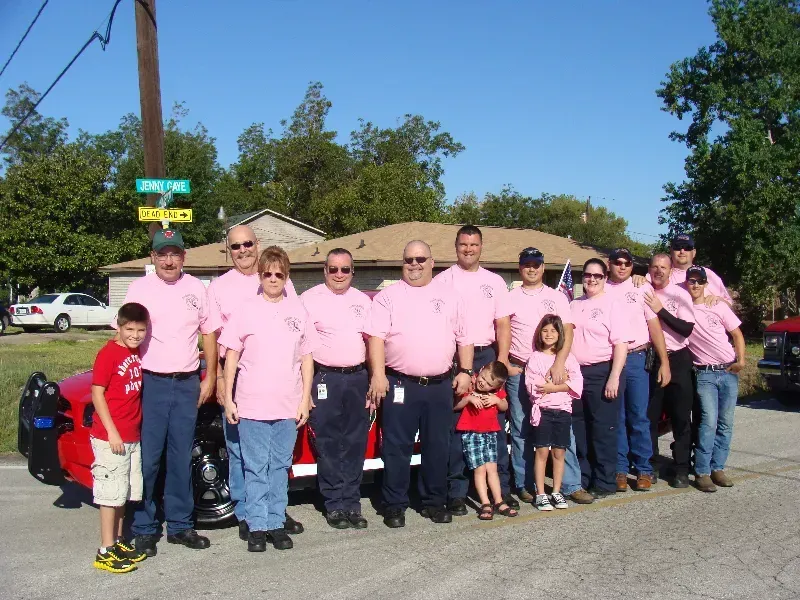 A group of people wearing pink shirts are posing for a picture