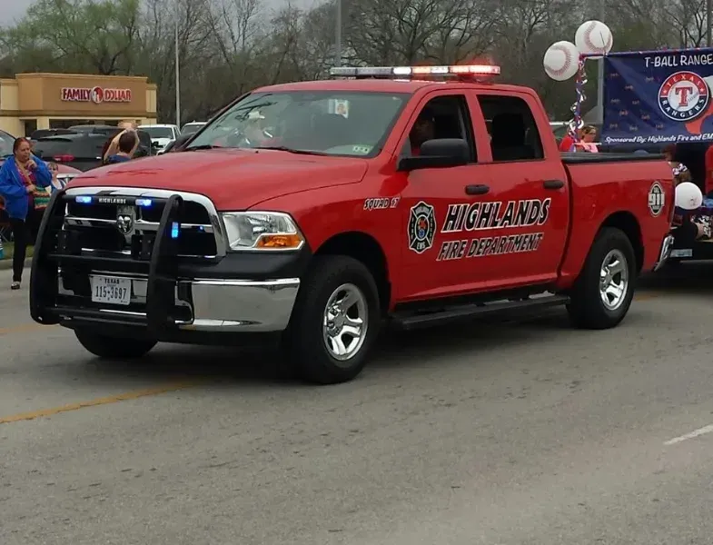A red command truck with the word Highlands Fire Department on it is driving in a parade.