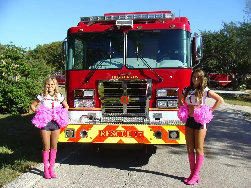 Two Houston Texans cheerleaders pose in front of a Highlands Fire truck Rescue 17