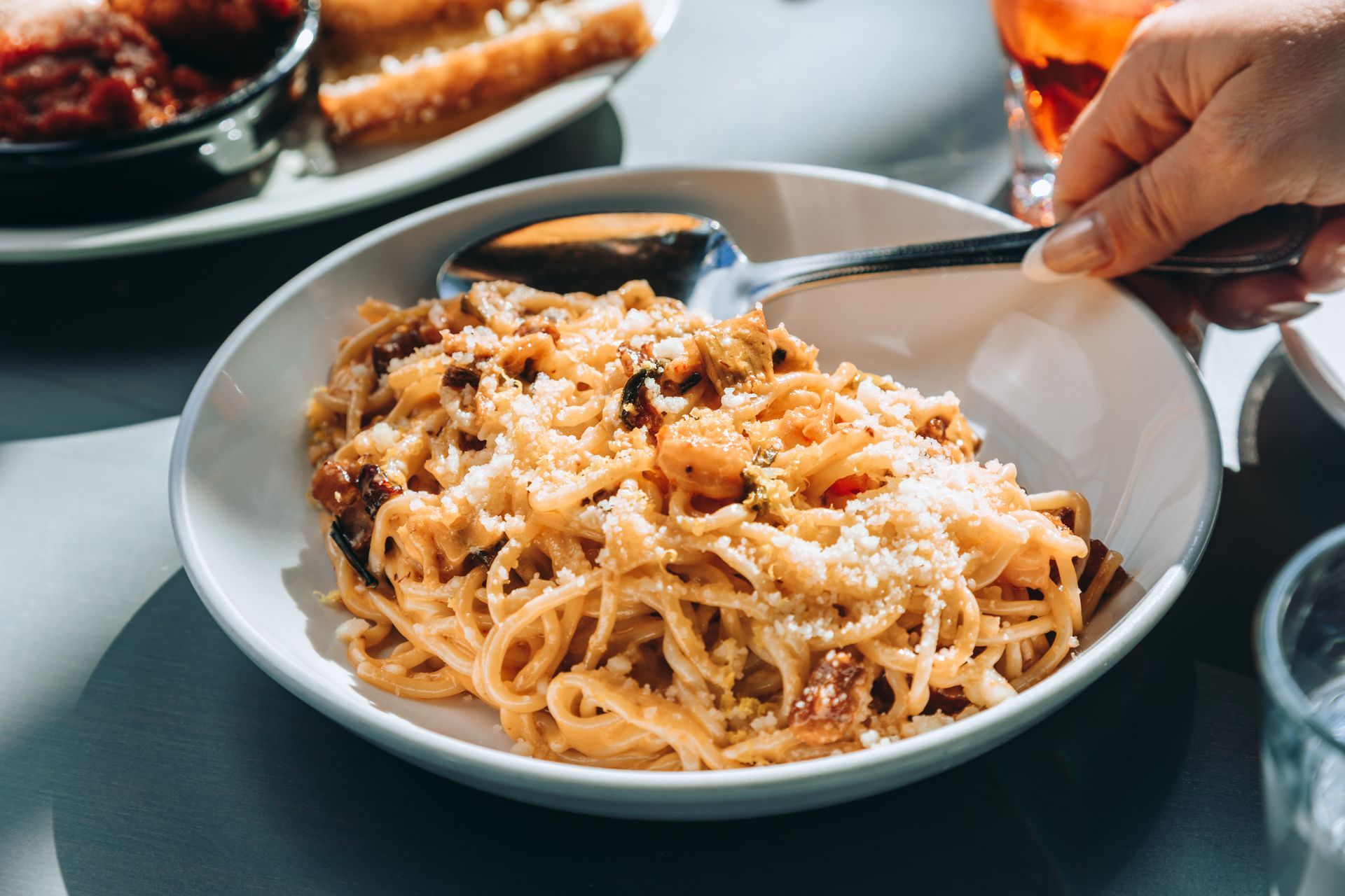 A person is taking a spoon out of a bowl of spaghetti.