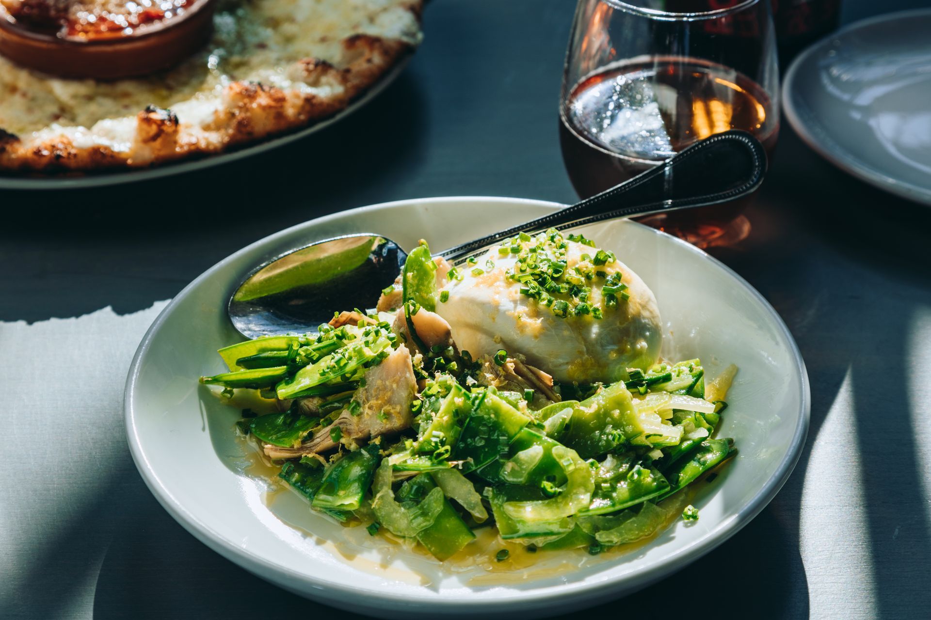 A plate of food with a spoon and a glass of wine on a table.