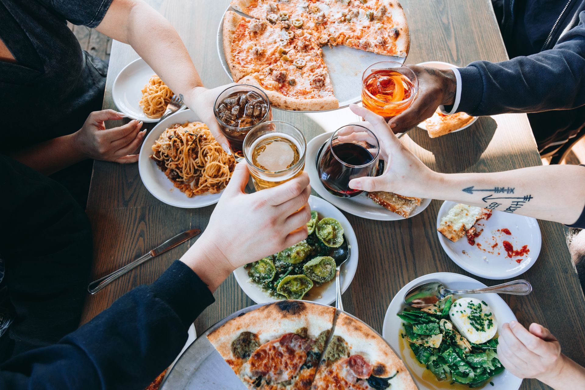 A group of people are sitting around a table eating pizza and drinking beer.