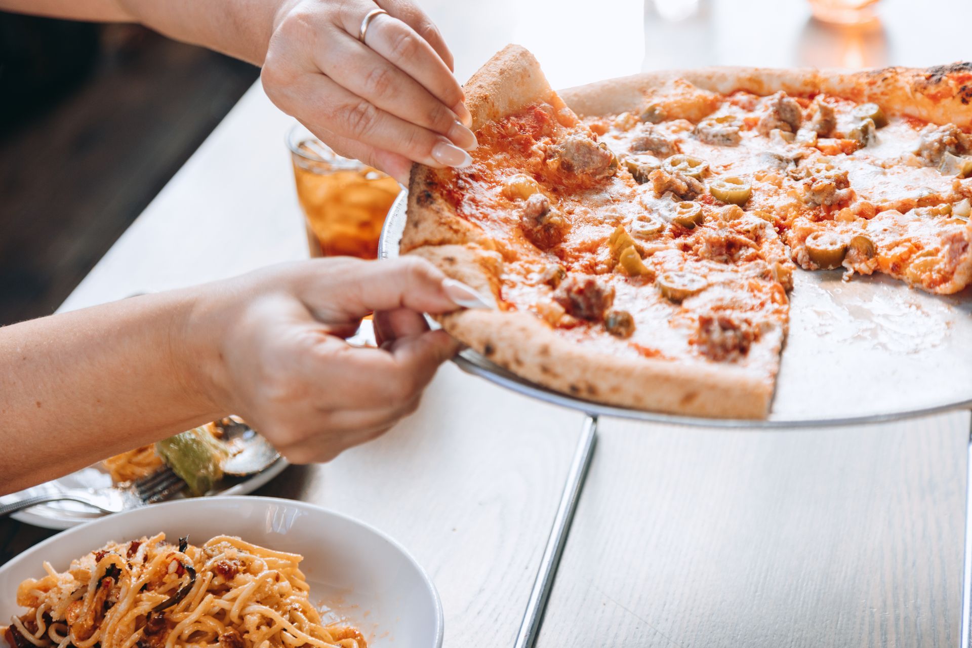 A person is taking a slice of pizza from a pizza pan.