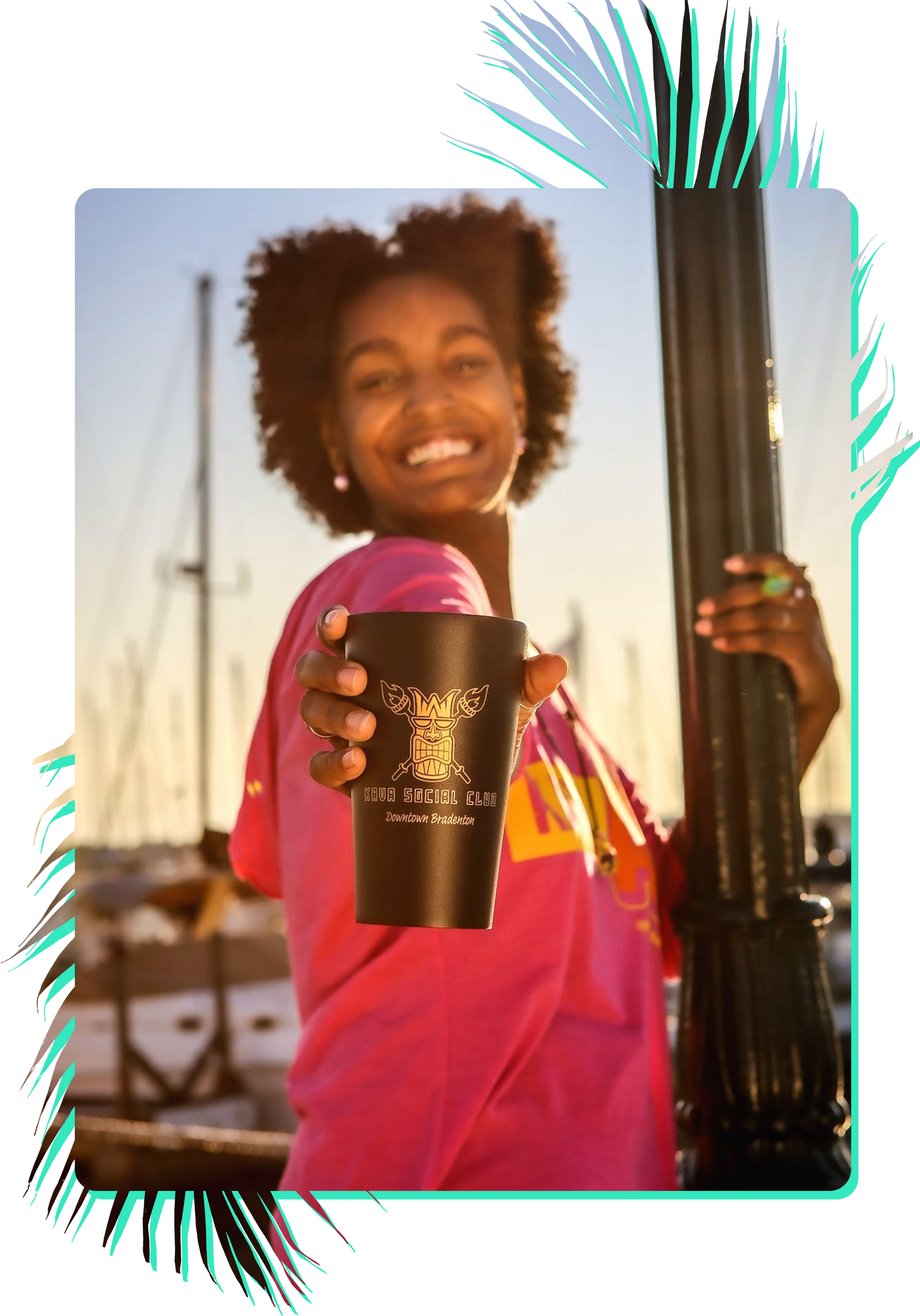 A woman in a pink shirt is holding a black cup and smiling.