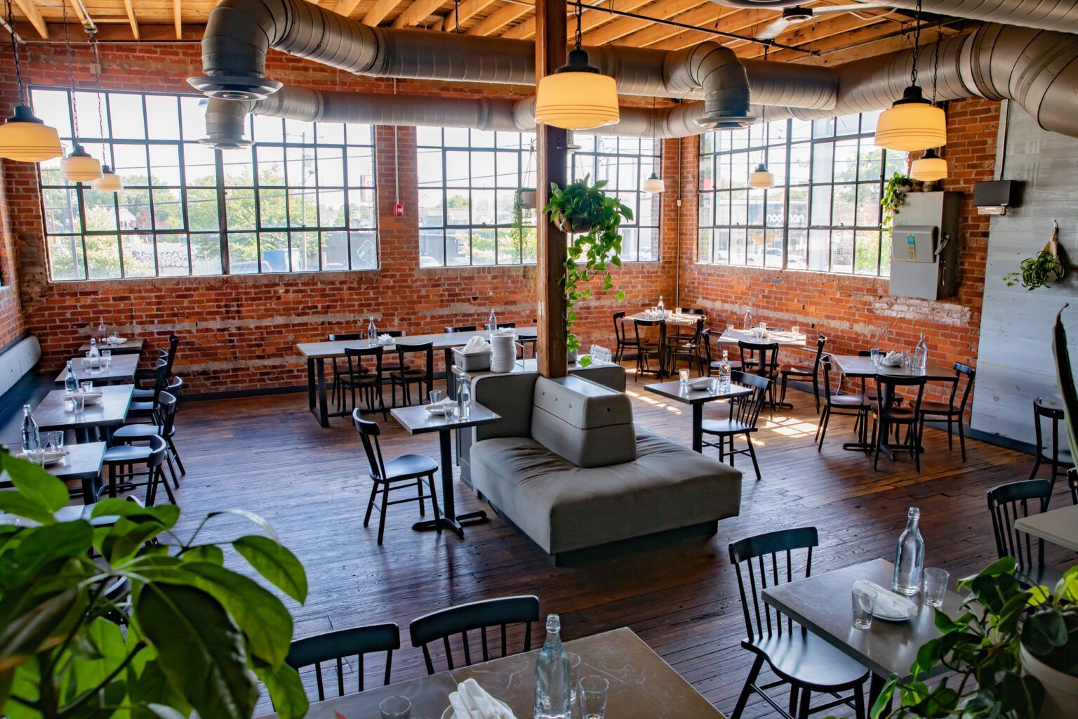 A large dining room with tables and chairs and a couch.