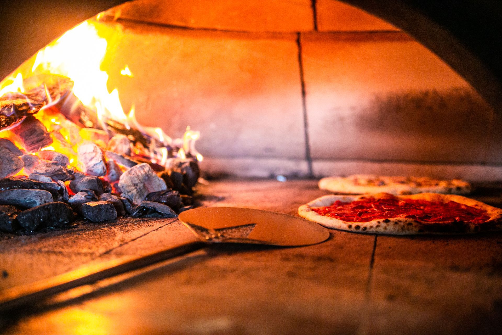 A pizza is being cooked in a wood fired oven.