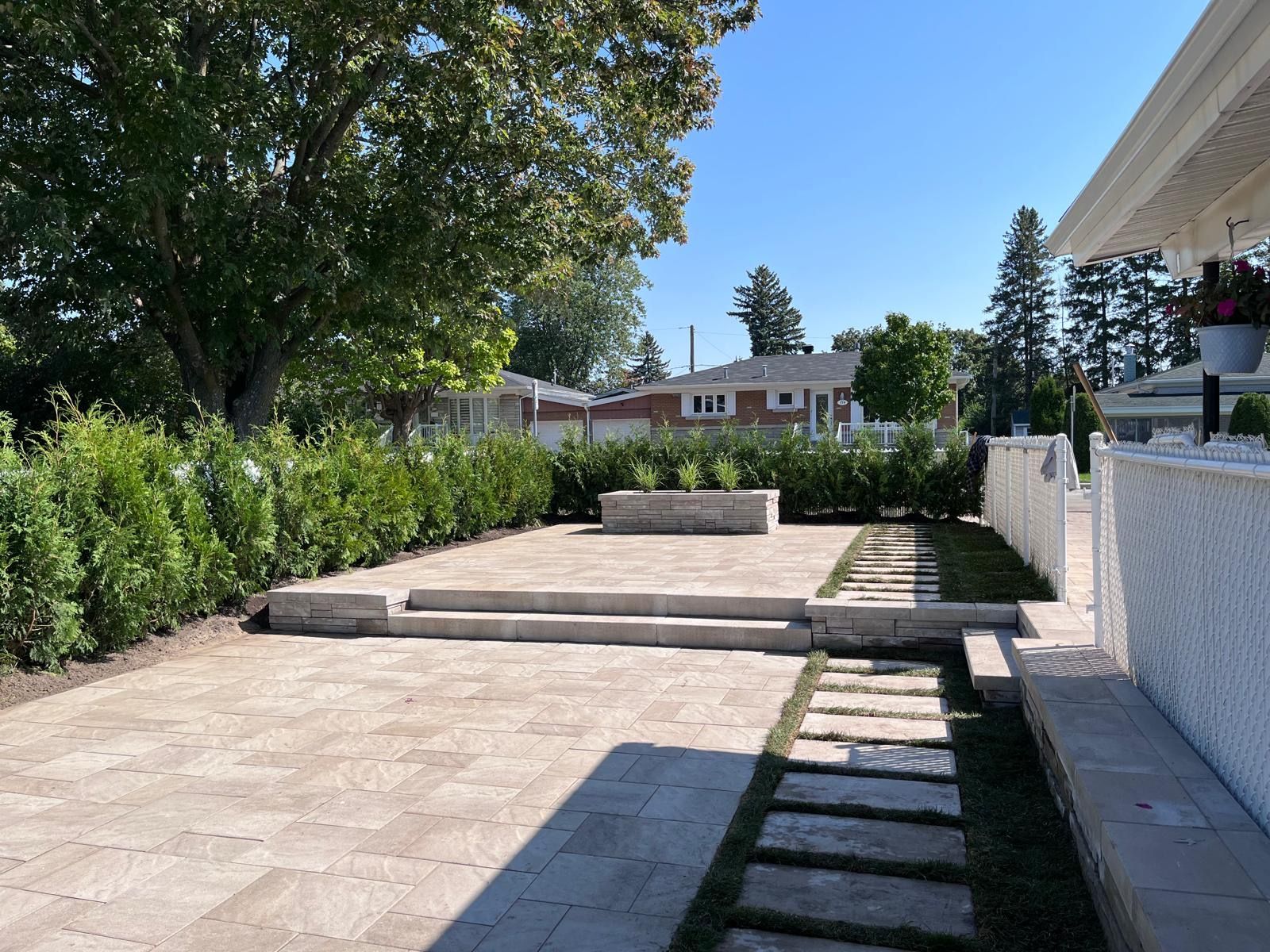 Un patio avec des marches menant à un banc et des arbres en arrière-plan