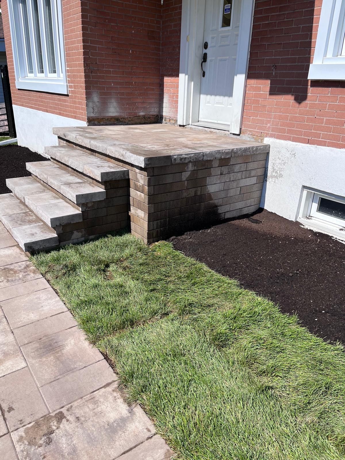 Une maison en briques avec des escaliers menant à la porte d'entrée.