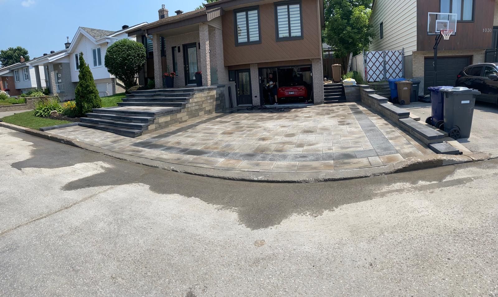 Une voiture est garée dans l'allée d'une maison à côté d'un panier de basket.