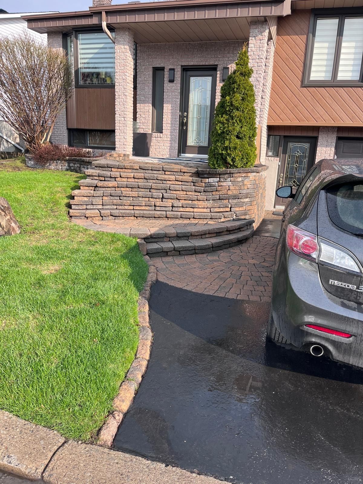 Une voiture est garée devant une maison avec des escaliers.