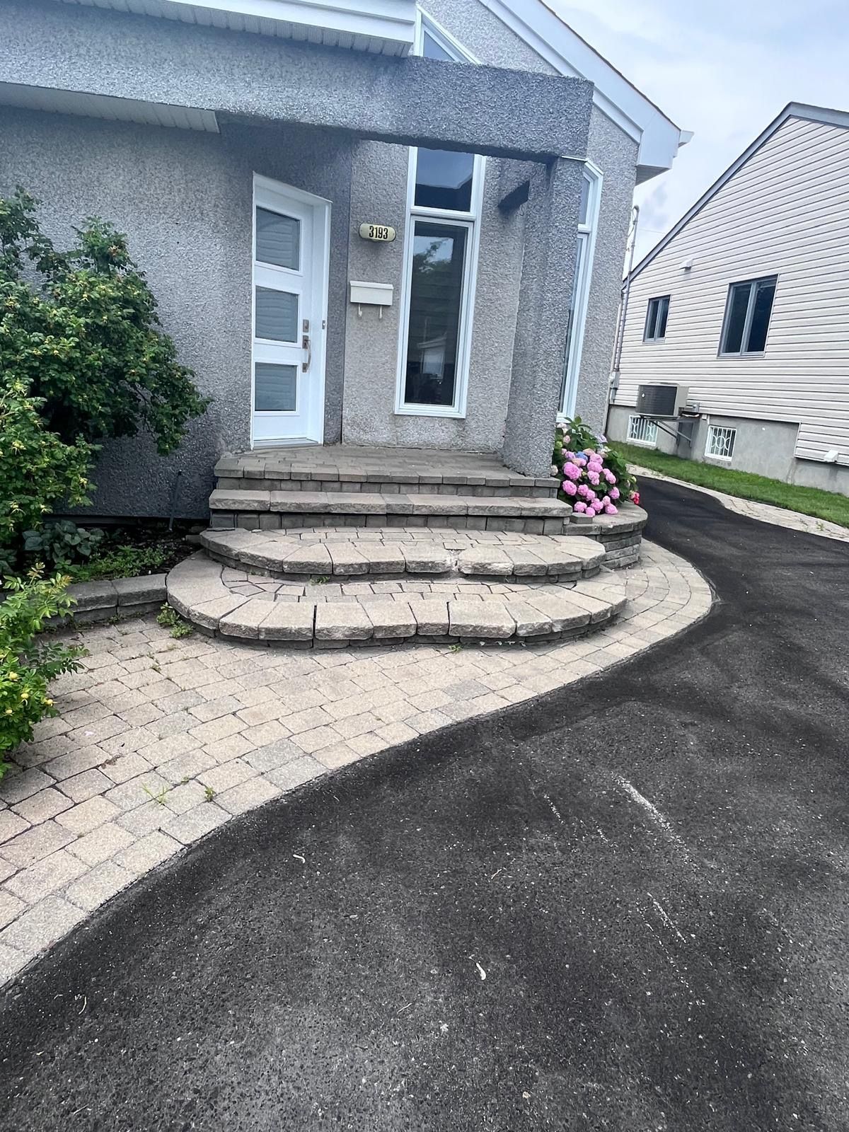 Une maison avec des escaliers menant à la porte d'entrée et une allée.