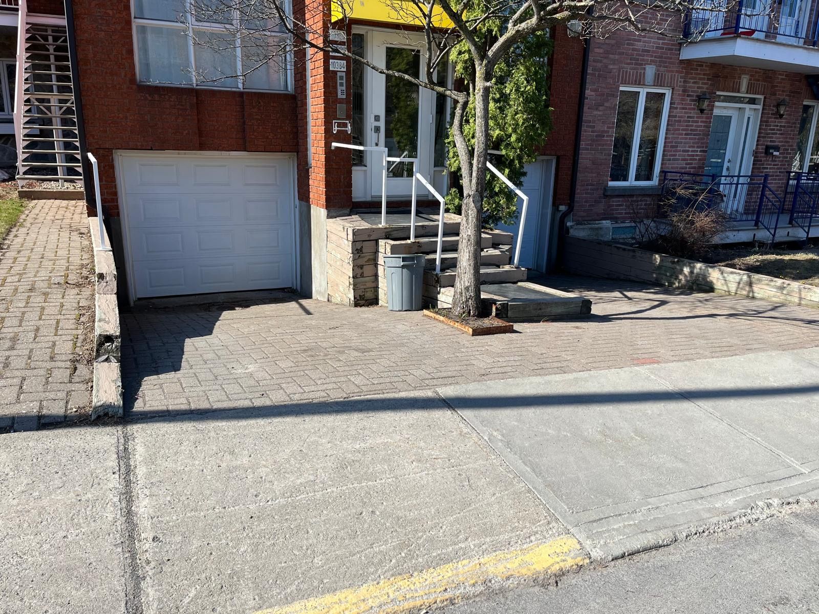 Une maison en briques avec une porte de garage blanche et des escaliers