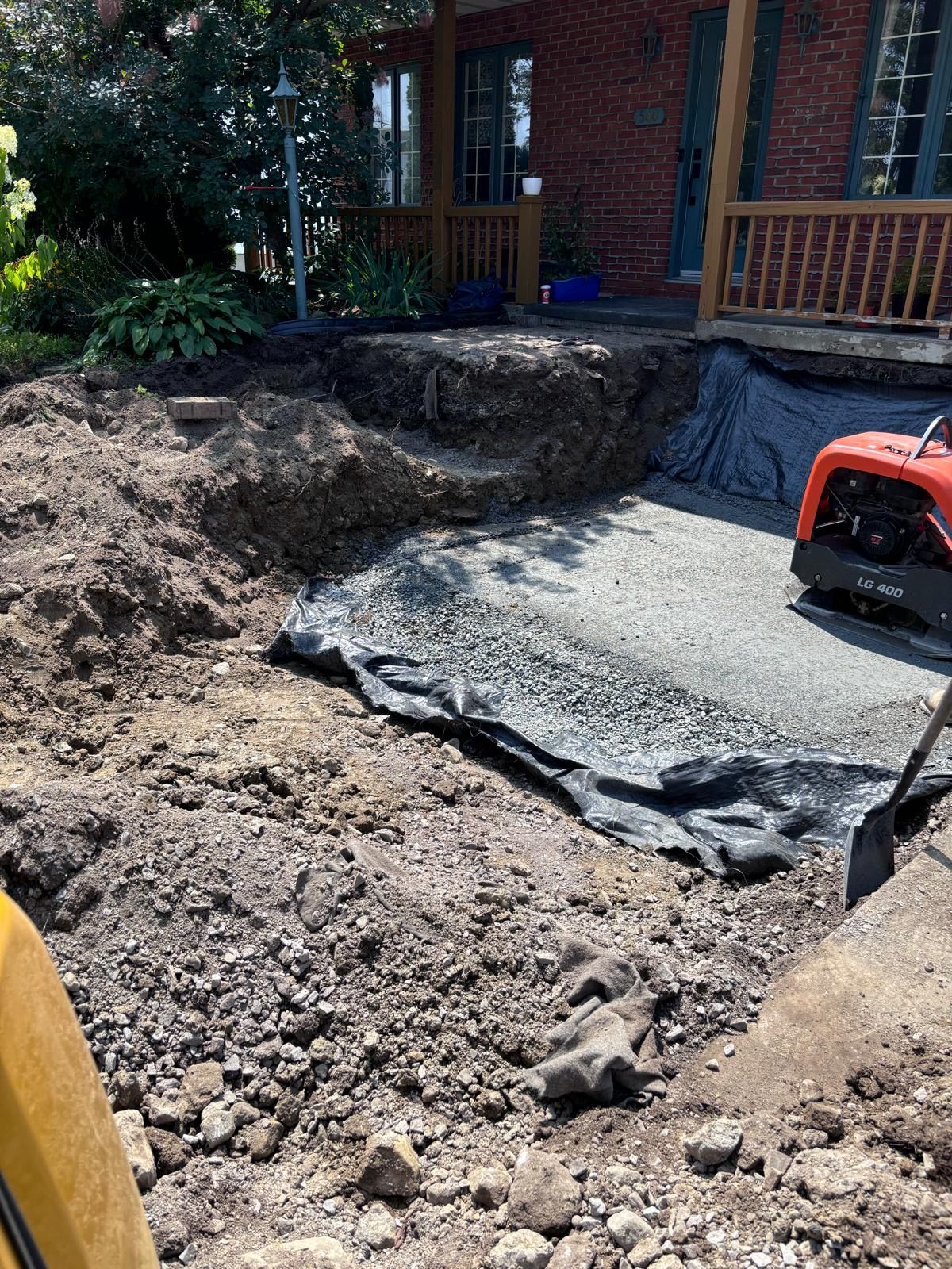 Un tracteur creuse un trou dans la terre devant une maison.