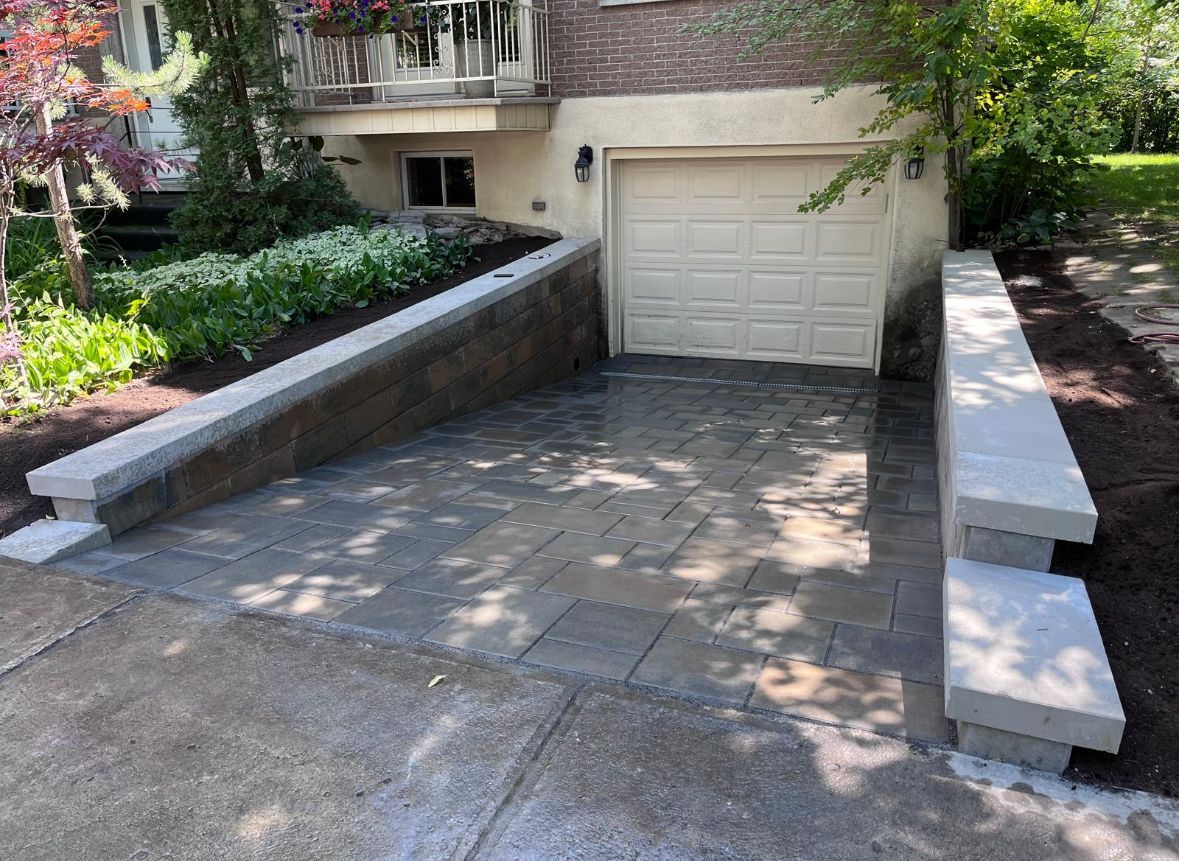 Une allée menant à un garage avec un mur de briques qui l'entoure.