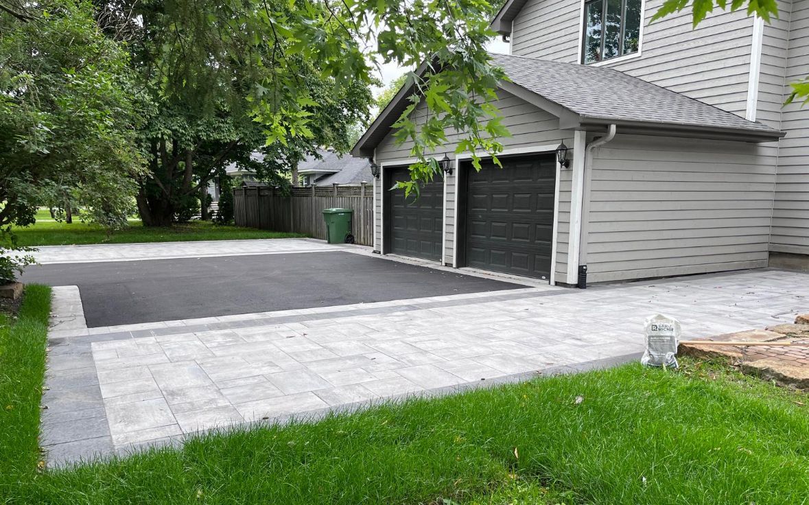 Une maison avec deux garages et une allée devant.