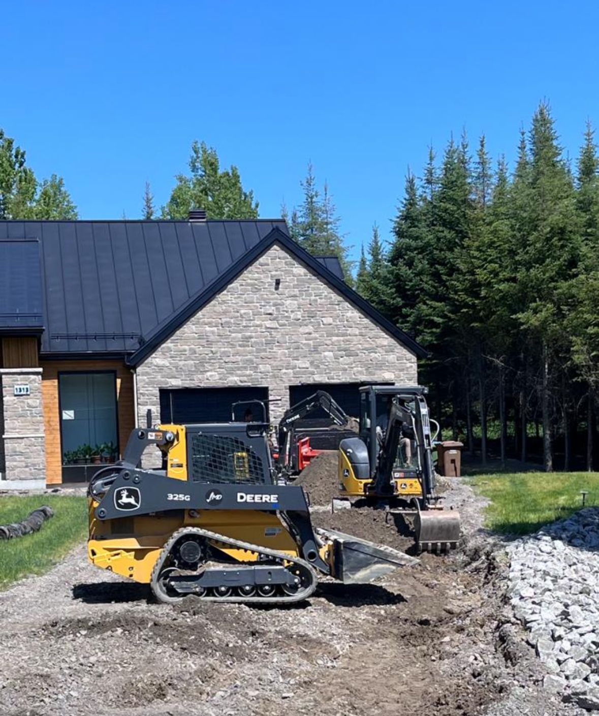 Un bulldozer John Deere est garé devant une maison.