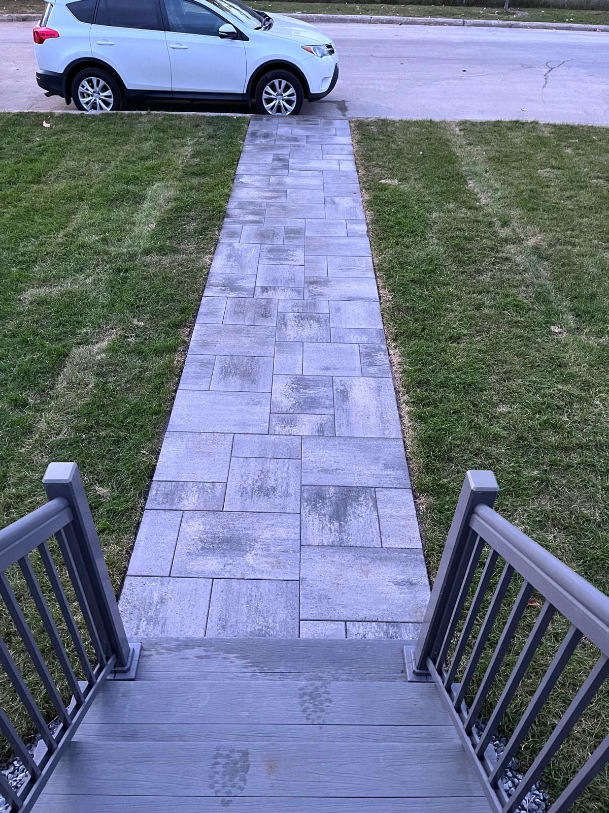 Une voiture blanche est garée sur le bord de la route à côté d'un trottoir.