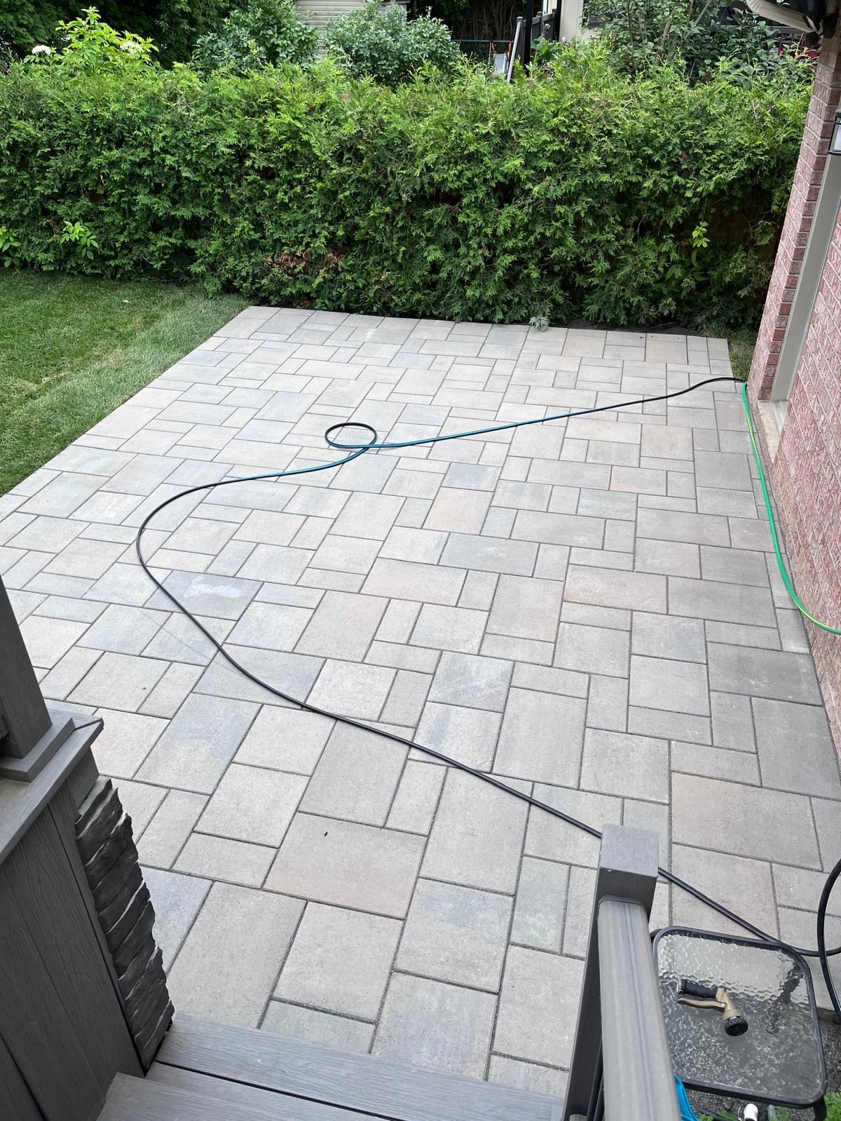 Un tuyau est posé sur un patio à côté d'une maison.
