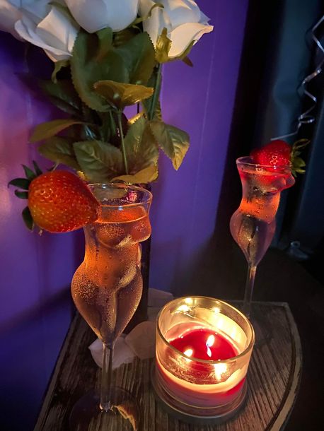 two wine glasses with strawberries and a candle on a table.