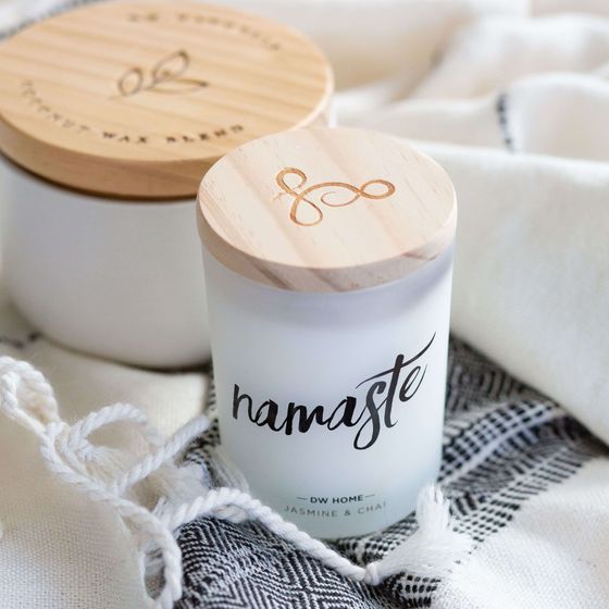 a candle with a wooden lid that says namaste