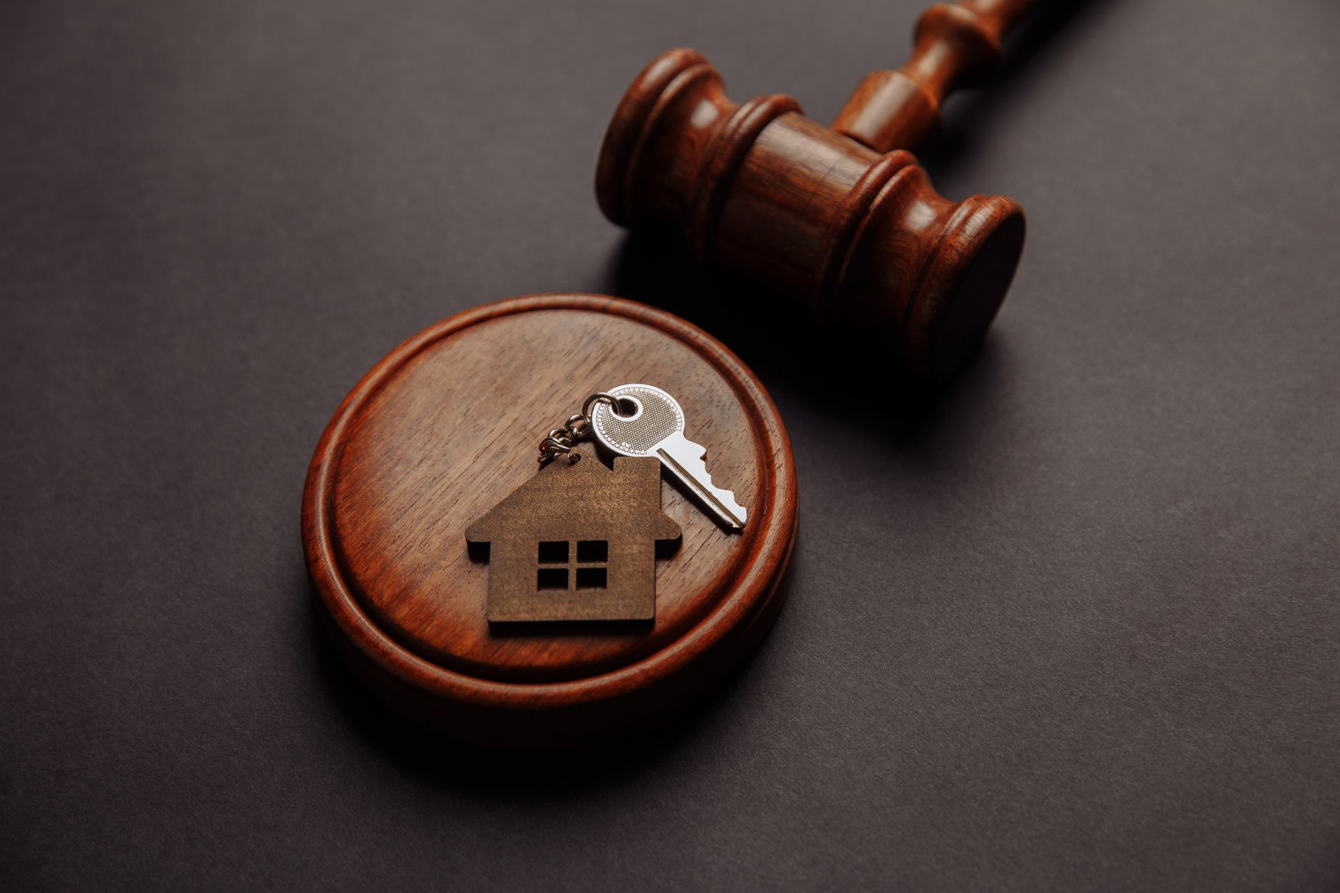 A wooden gavel with a house and keys on it.