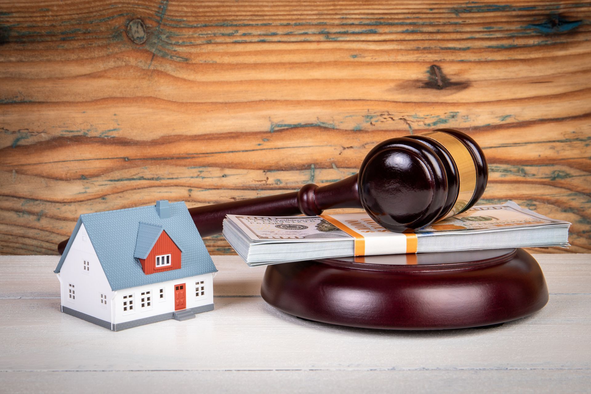 A judge 's gavel is sitting on top of a stack of money next to a small house.