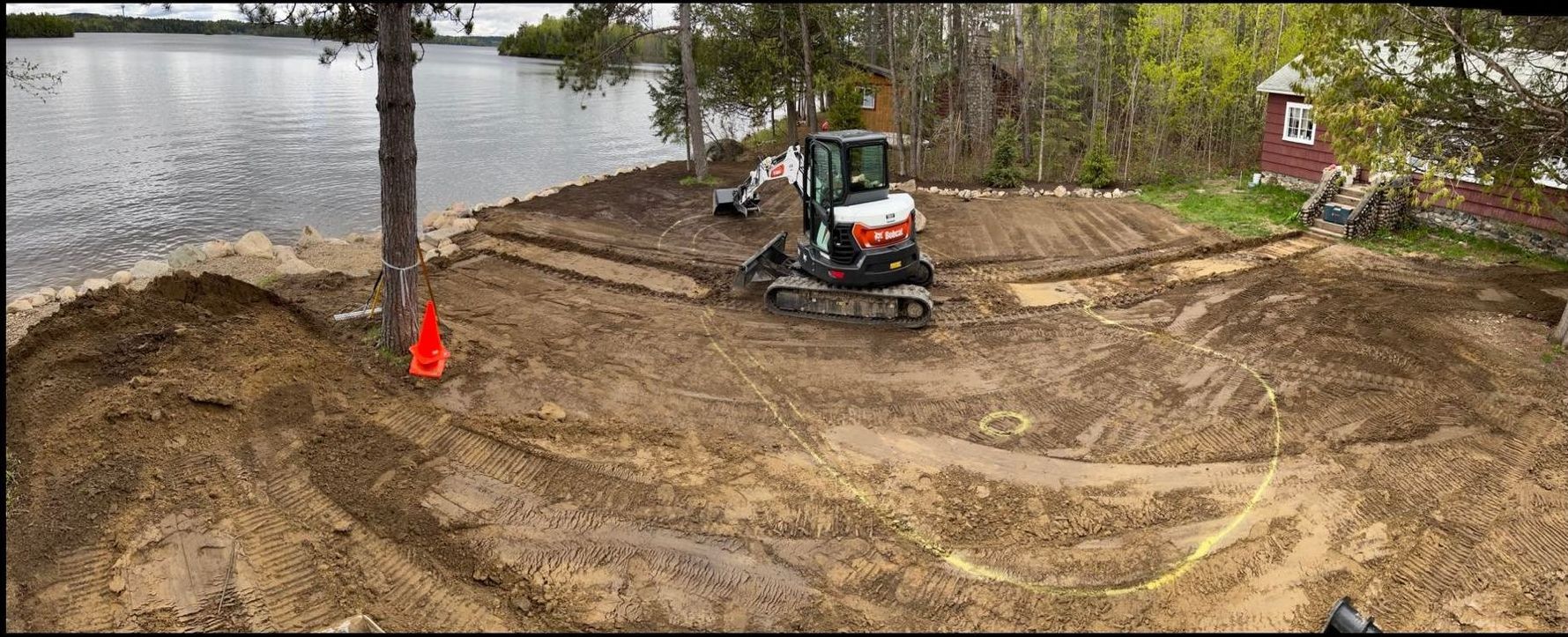 A bulldozer is digging a hole in the dirt near a lake.