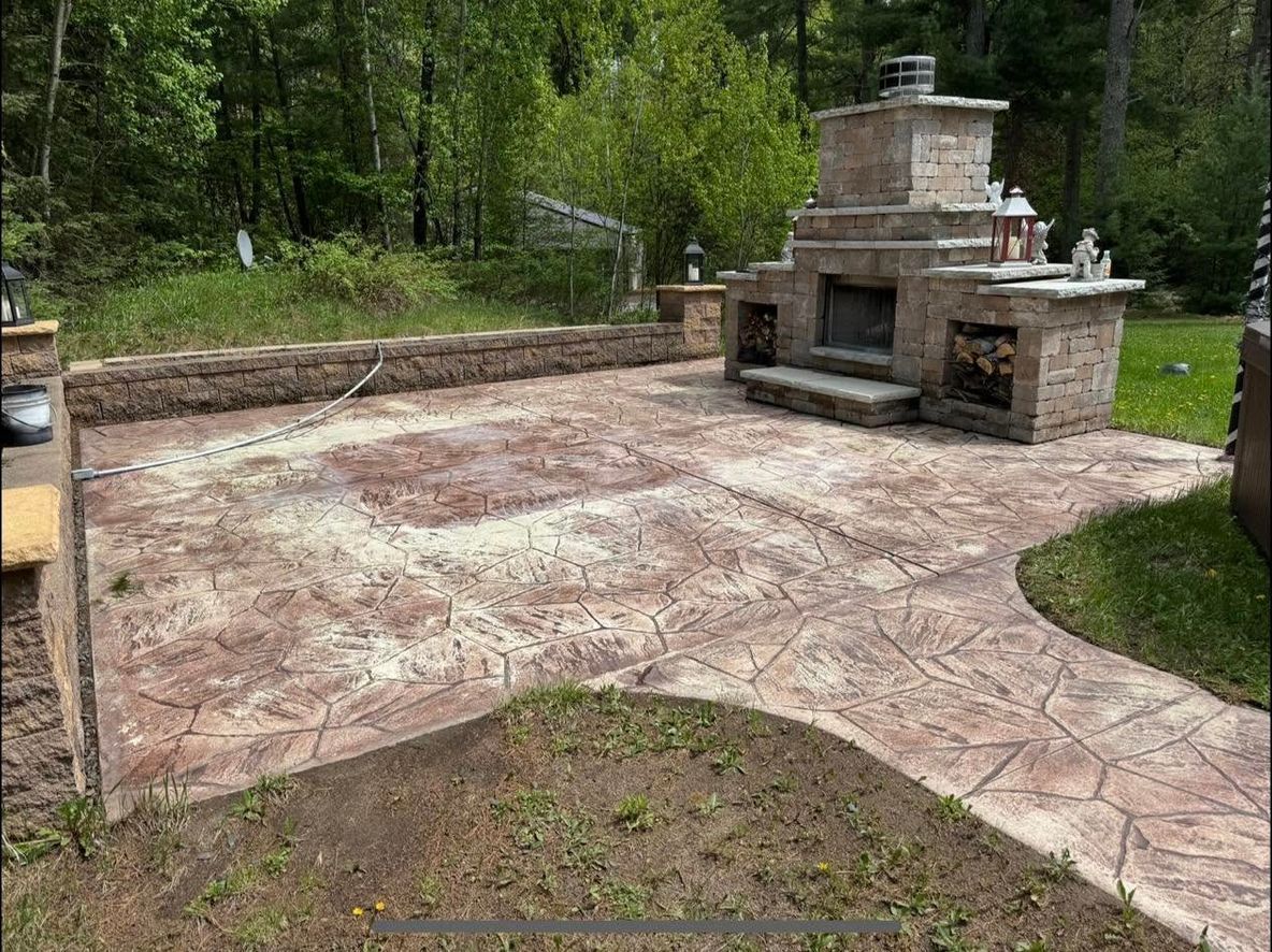 A patio with a fireplace and a walkway in the backyard.