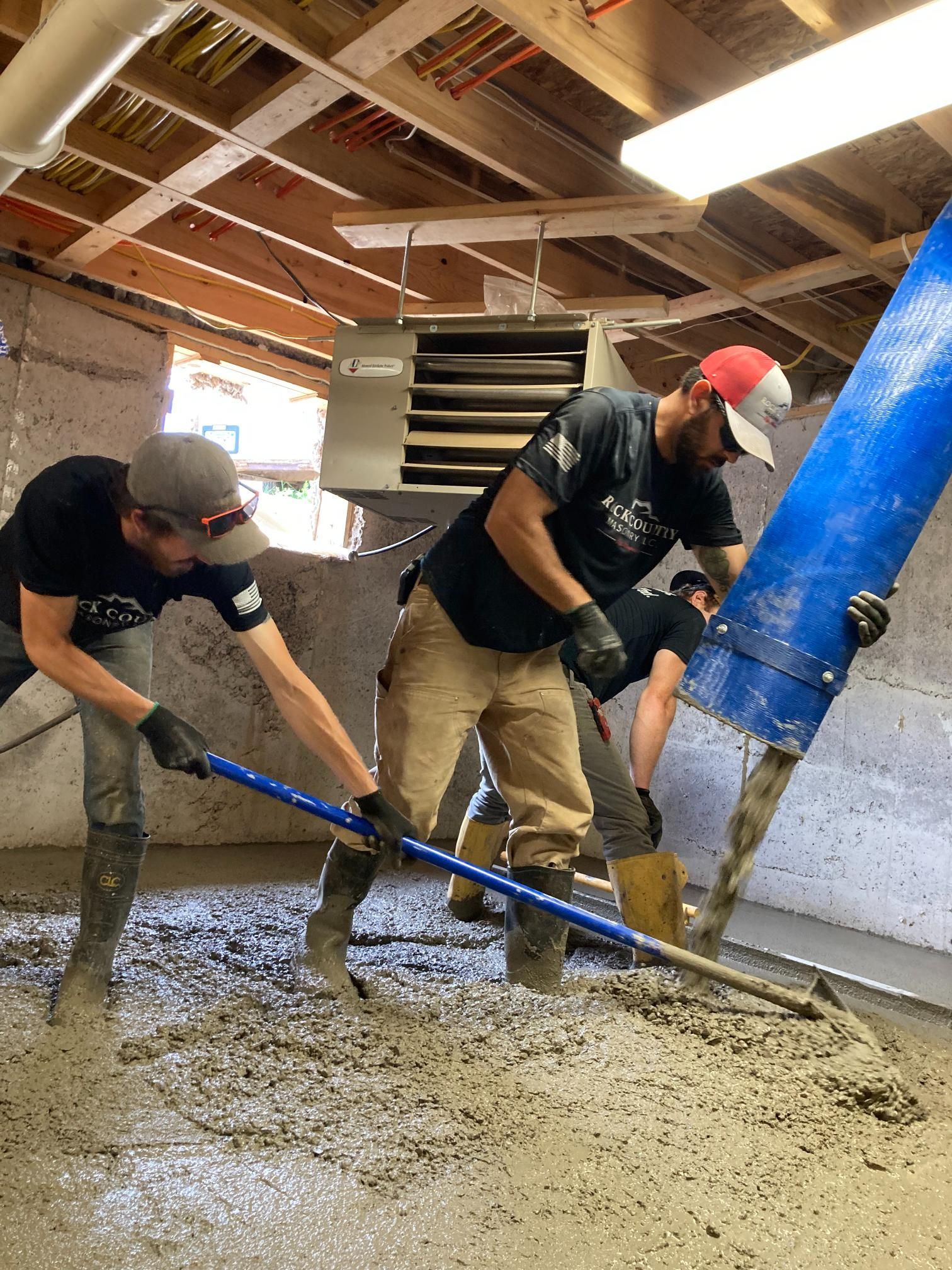 Two men are pouring concrete into a room.