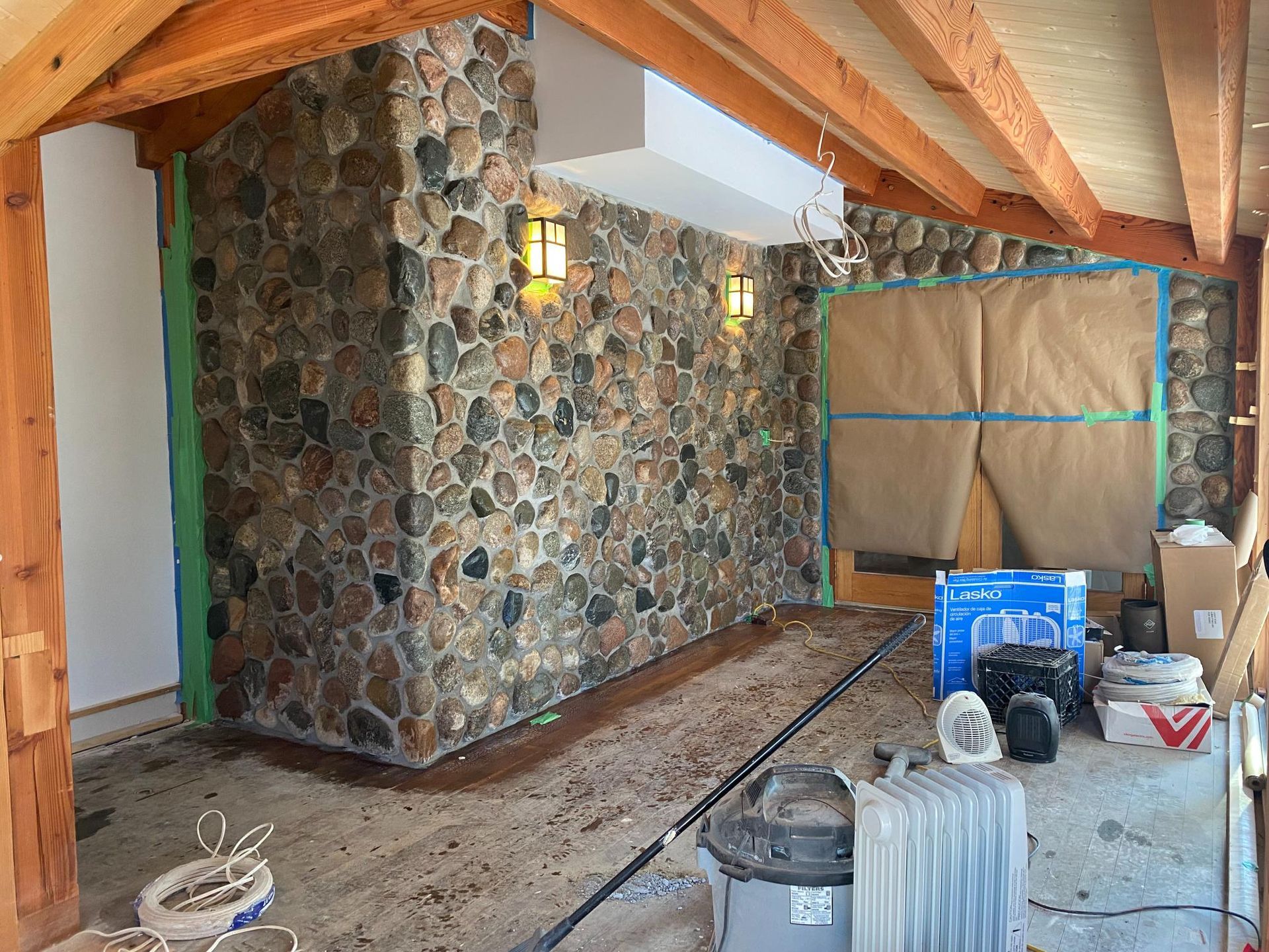 A room with a stone wall and a vacuum cleaner on the floor.