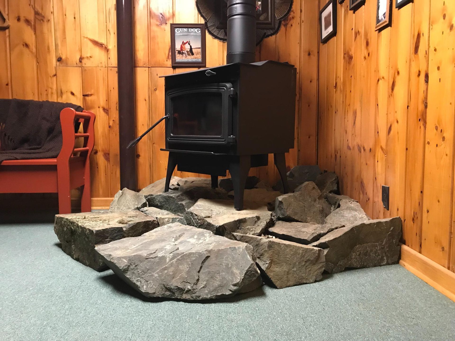 A wood stove is sitting in a room with wood paneling